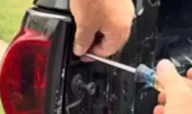 Removing the Phillips screws from the tail light assembly.