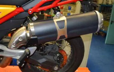 Final installation of the muffler on the motorcycle.